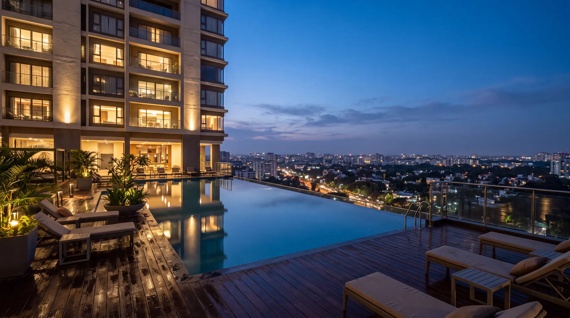A rooftop infinity pool beside a luxury residential tower above the Bengaluru skyline at blue hour